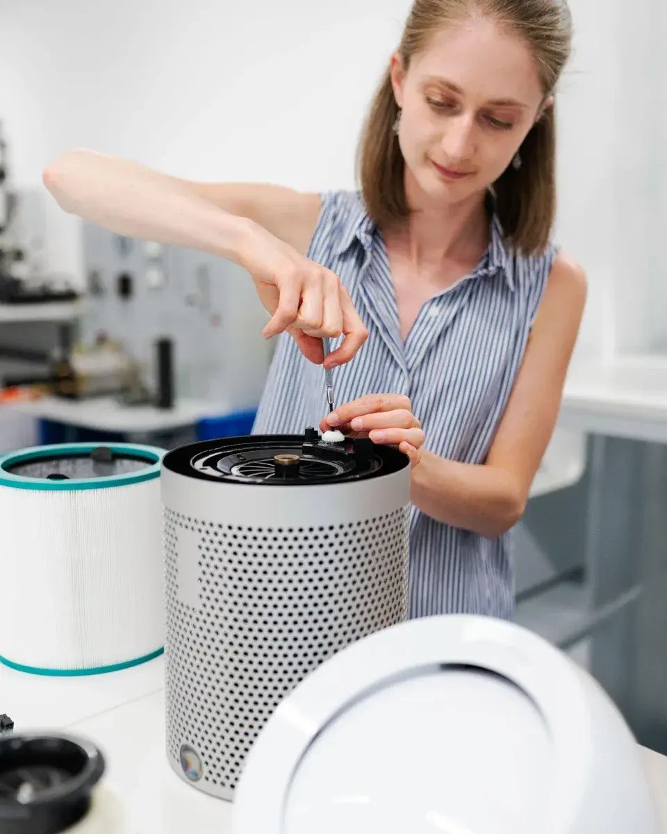 Engineer assembling an air purifier with a cylindrical filter in a development lab, representing new indoor air quality solutions
